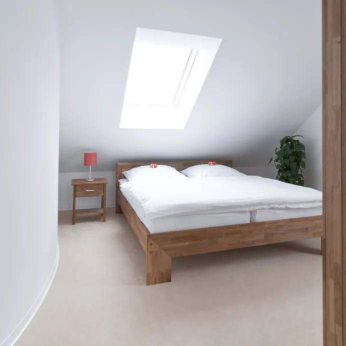 Schlafzimmer unter dem Dach mit hellem Teppichboden
