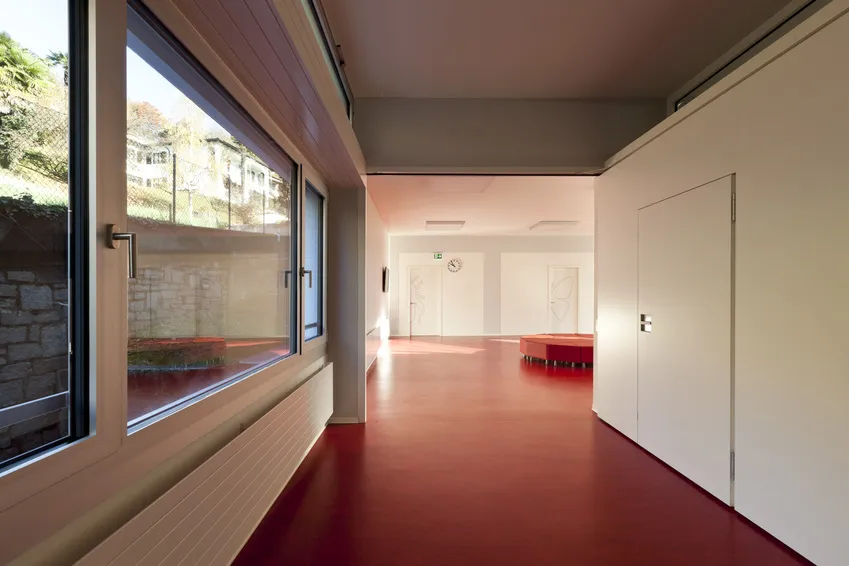 Breiter Korridor mit rotem Linoleum-Designbelag und Fensterfront